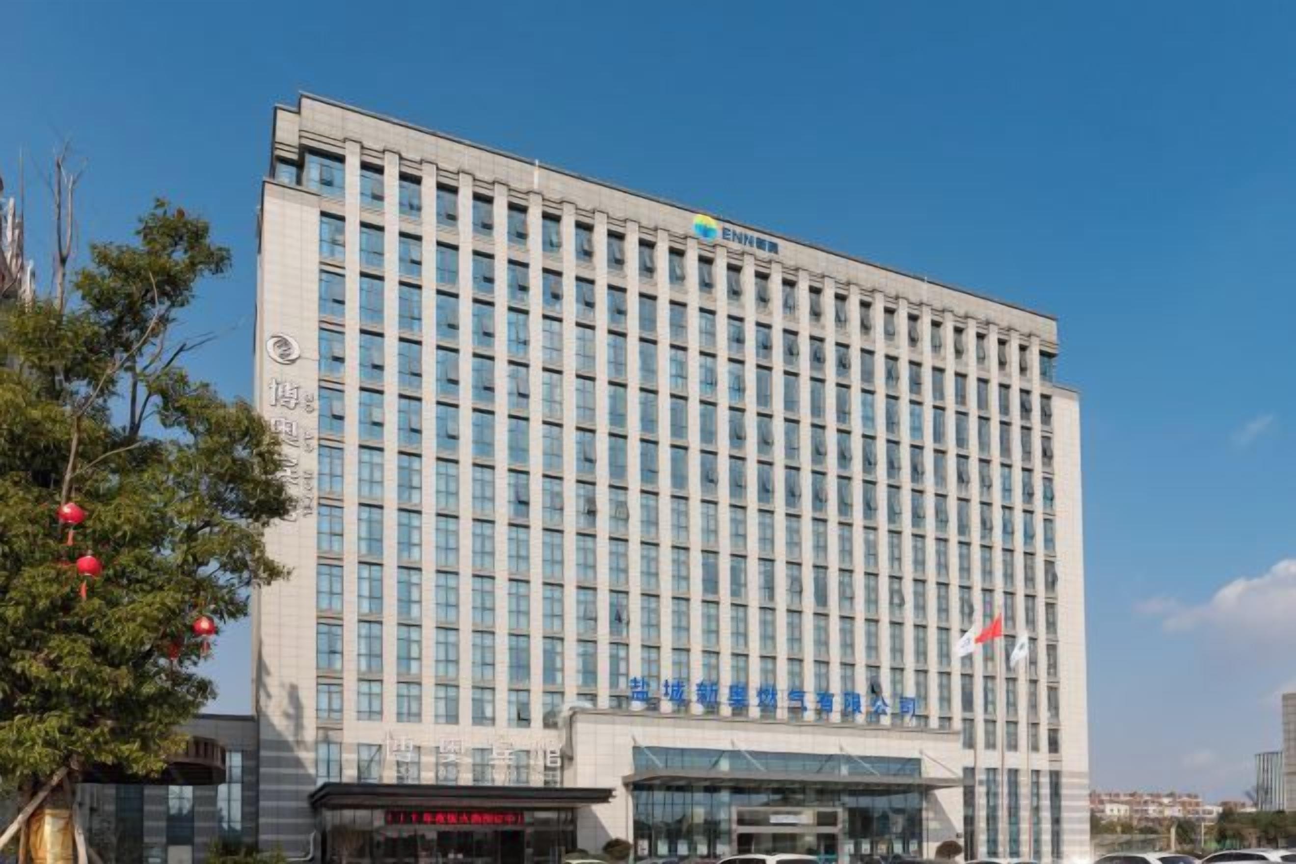 A multi-story building with a modern architectural design, featuring a prominent entrance with glass doors and a flag on top.
