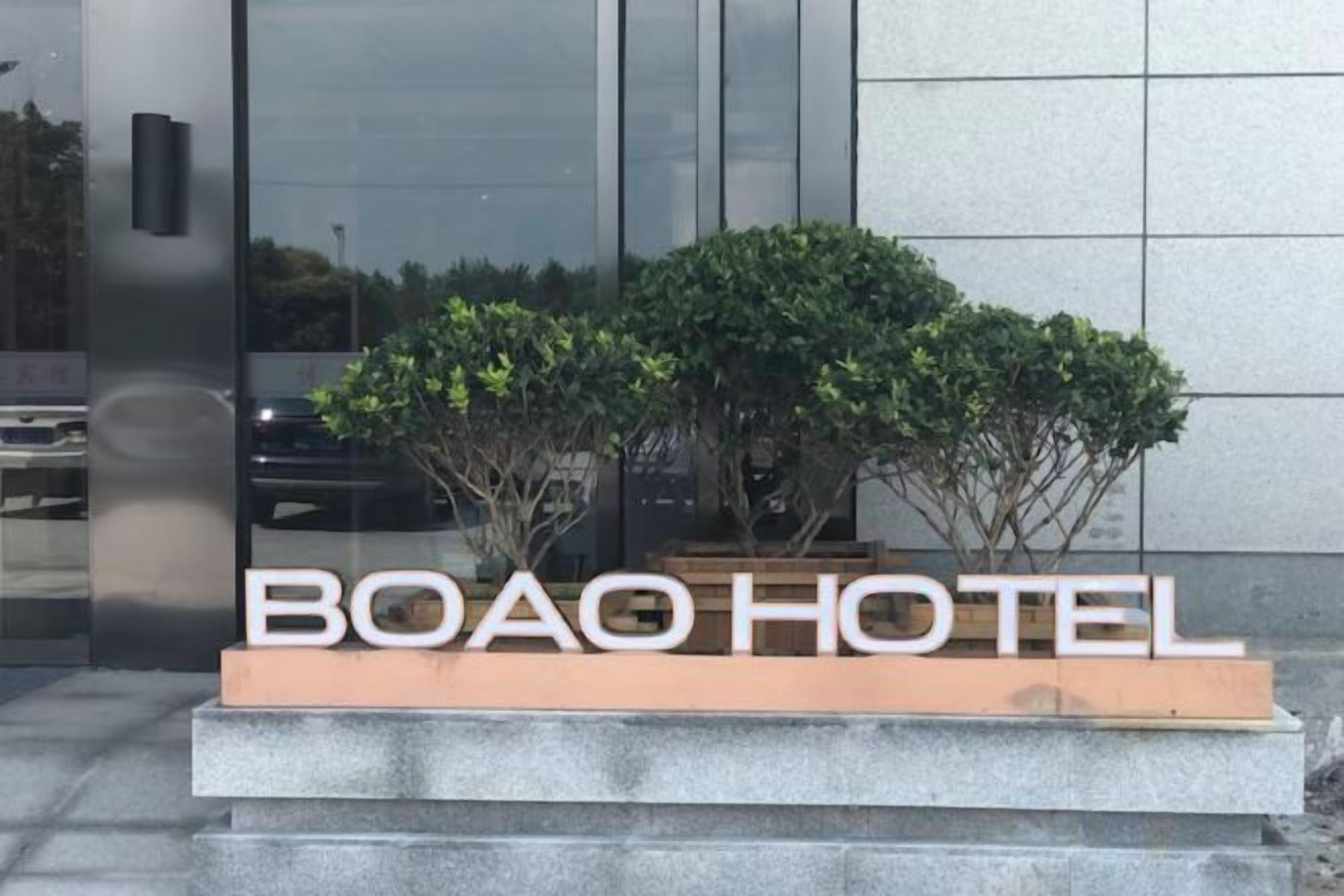 A sign for BOAO HOTEL with a modern design, featuring a clear view of the building's facade and a landscaped area with shrubs.