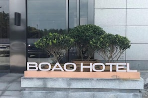 A sign for BOAO HOTEL with a modern design, featuring a clear view of the building's facade and a landscaped area with shrubs.