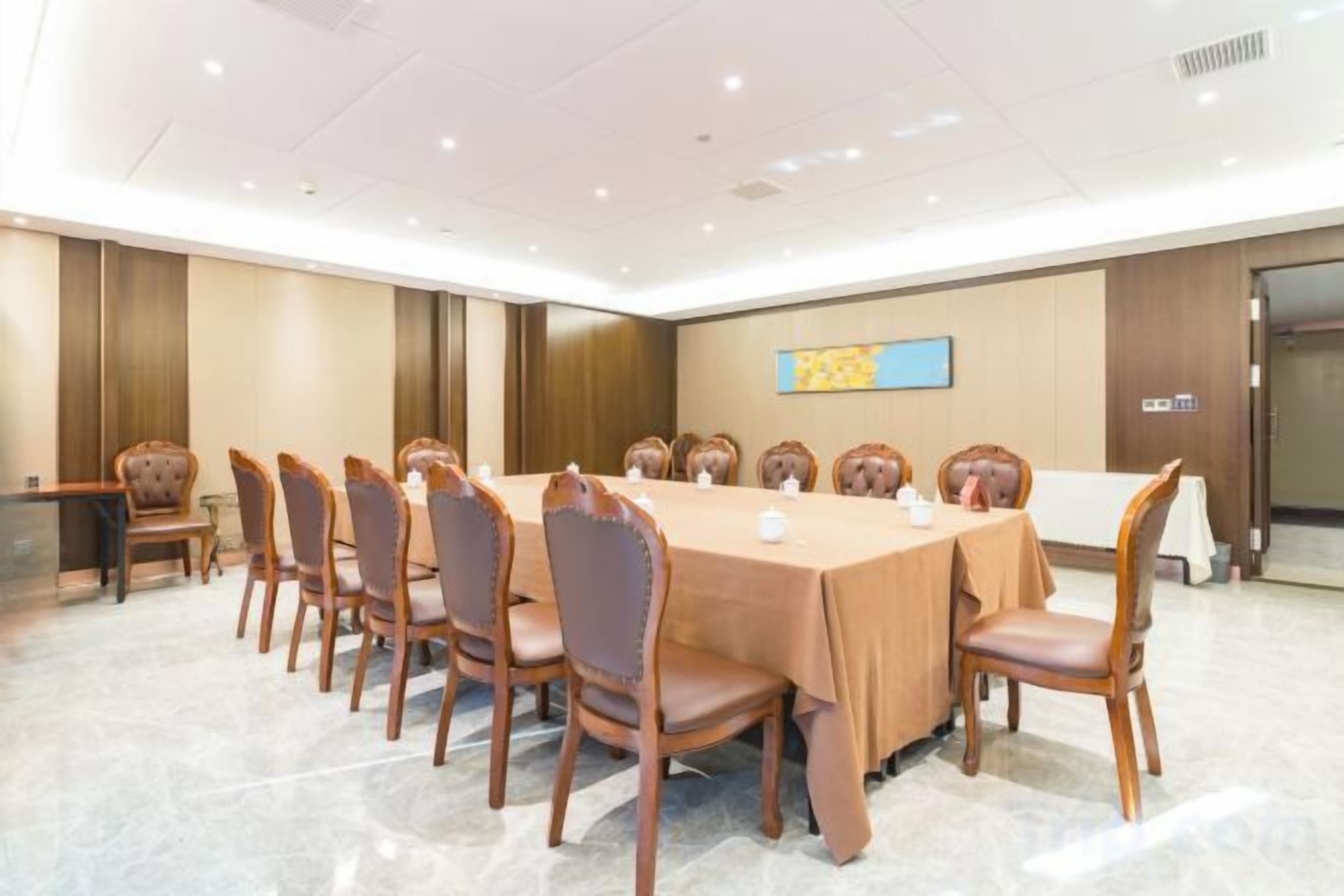 Un salón de conferencias con una larga mesa, varias sillas y una pizarra en la pared.