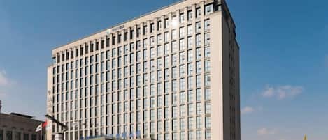 Un edificio de hotel de varios pisos con entrada de vidrio y un cielo despejado.