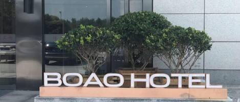 A sign for BOAO HOTEL with a modern design, featuring a clear view of the hotel's name and a reflection of the surrounding area in the glass facade.