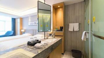 Una habitación de hotel con cama, baño con lavamanos, espejo y ducha.