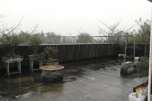 An outdoor patio area with a round table and several potted plants. - Changtai Dongyuan Hotel (Zhangzhou)