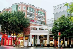 A multi-story building with a prominent OYO hotel sign, surrounded by various shops and a tree-lined street. - Changtai Dongyuan Hotel (Zhangzhou)