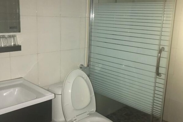 A bathroom with a toilet, a sink, and a glass shower enclosure. - Changtai Dongyuan Hotel (Zhangzhou)