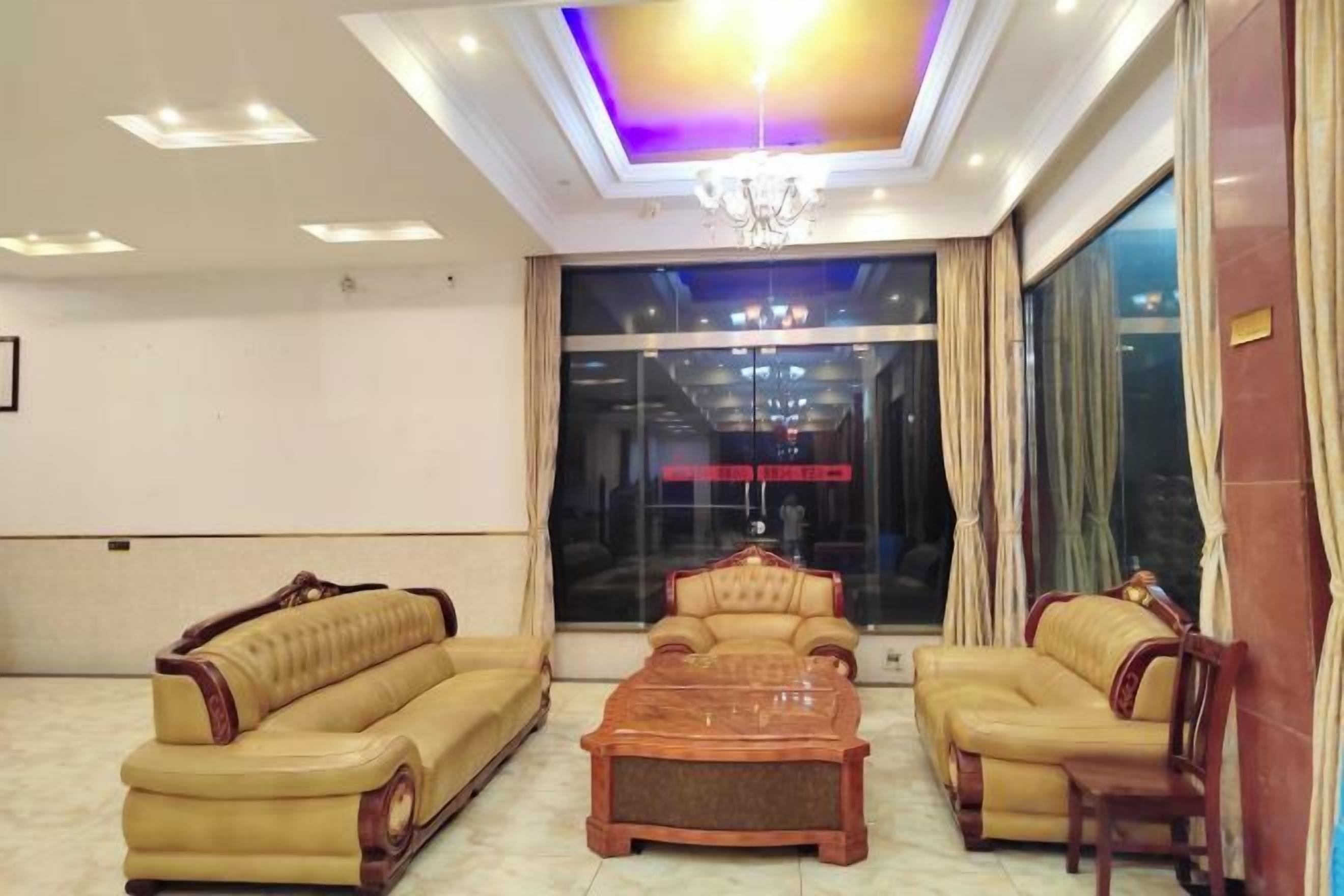 A hotel lobby with a reception desk, two sofas, a coffee table, and a chandelier.