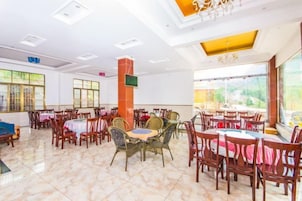 Un comedor amplio con varias mesas y sillas, un pilar central y grandes ventanales que dejan entrar luz natural.
