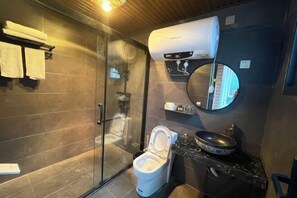 A modern bathroom with a glass shower enclosure, a toilet, a sink with a round mirror, and a towel rack with folded towels. - Shunan Bamboo Sea Shuangfeng Boutique Homestay (Changning)