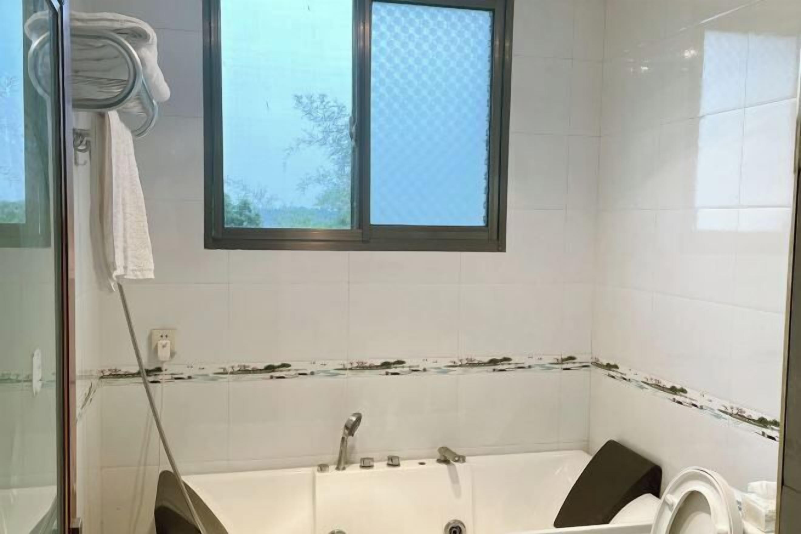 A bathroom with a bathtub, a window, and a shower area.