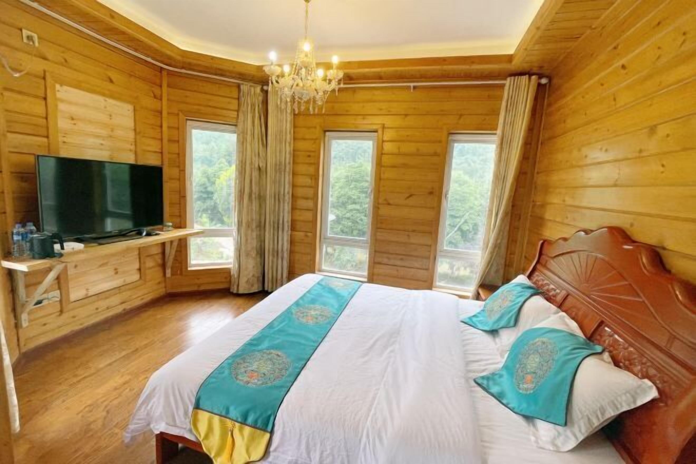 Ein Zimmer in einer Holzhütte mit einem Bett, einem Fernseher und einem Fenster.