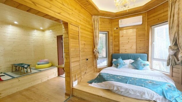 Ein Holzblockhaus-Innenraum mit Bett, einem kleinen Tisch und einem Fenster.