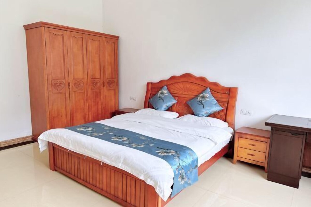 A bedroom with a wooden bed, a nightstand, a wooden wardrobe, and a desk.