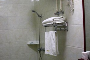 A shower area with a towel rack holding folded towels, a handheld showerhead, and a wall-mounted faucet. - Cixi Naya Hotel (Cixi)