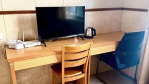 A corner office with a wooden desk, a television, a coffee maker, and a blue chair. - Cixi Naya Hotel (Cixi)