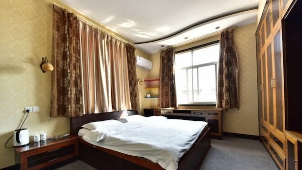 A hotel room with a large bed, a desk with a computer, a wardrobe, and a window with curtains. - Cixi Naya Hotel (Cixi)