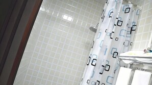 A bathroom with a tiled wall, a shower curtain with a geometric pattern, and a white sink with a mirror. - Cixi Naya Hotel (Cixi)