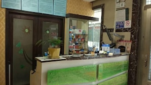 A reception desk with a potted plant, a mirror, and a counter with various items. - Cixi Naya Hotel (Cixi)