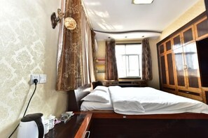 Ett hotellrum med en säng, gardiner, en garderob och ett fönster.