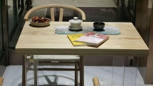 Una mesa de comedor con un bol de aperitivos, una tetera, una taza y dos libros.