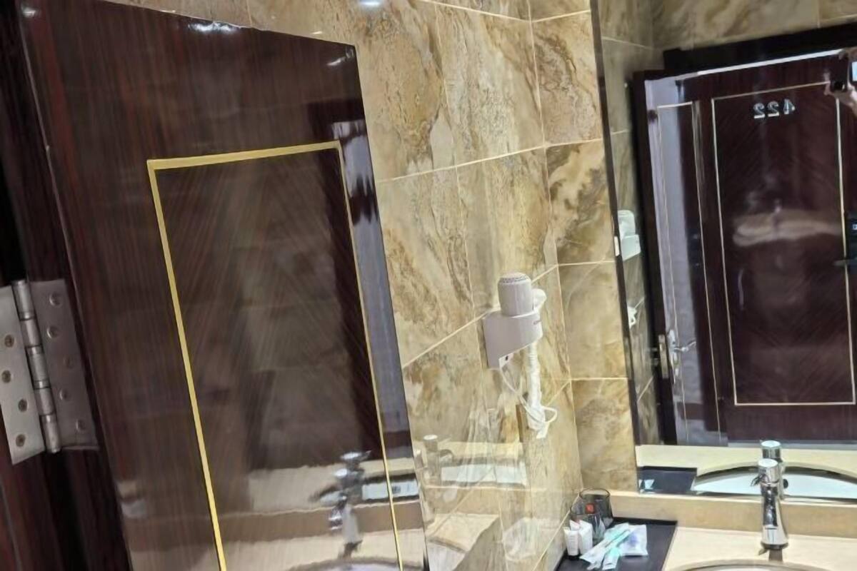 Une salle de bain avec un sol en marbre, un miroir, un lavabo et un porte-serviettes.