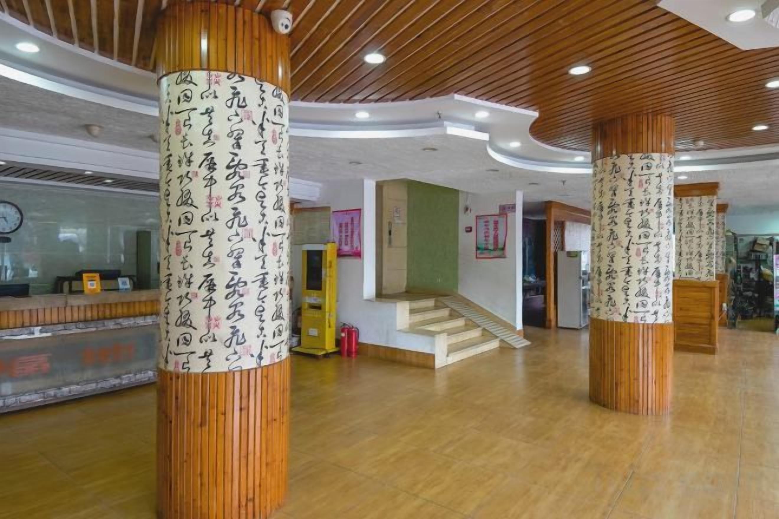 Un hall d’entrée avec des colonnes en bois, un comptoir d’accueil et un escalier.