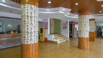 Un hall d’entrée avec des colonnes en bois, un comptoir d’accueil et un escalier.