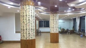 A spacious lobby with wooden pillars featuring calligraphy, a modern ceiling design, and a view of the interior. - Yushan Chunhui Express Hotel (Yushan)