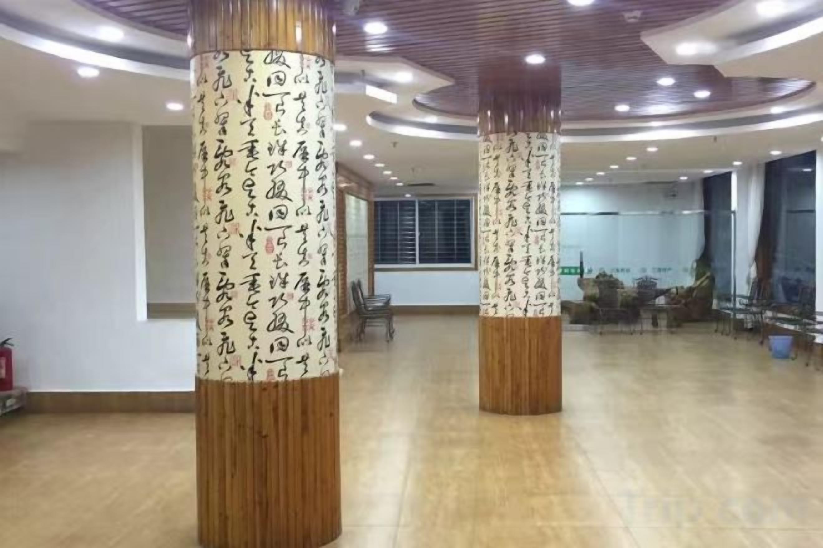 Amplia habitación con pilares de madera que presentan caligrafía, un ventanal grande y un diseño de techo moderno.