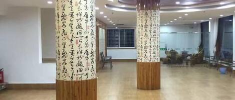 A spacious room with wooden pillars featuring calligraphy, a large window, and a modern ceiling design.