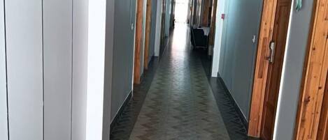 Un pasillo con taquillas, piso estampado y puertas a ambos lados.