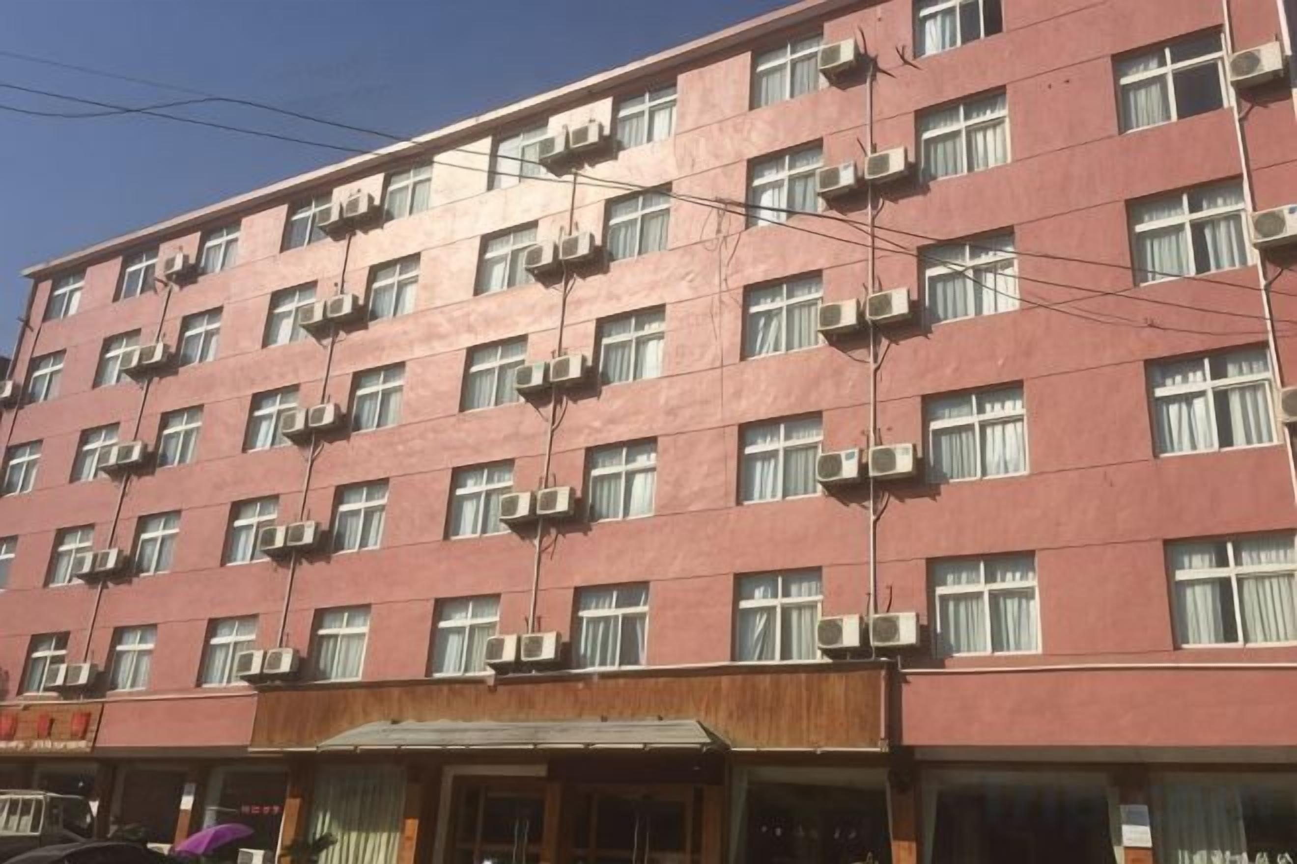 A multi-story building with numerous windows and air conditioning units.