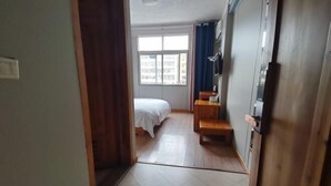 A hotel room with a bed, a desk, a chair, and a window with a view of buildings. - Yushan Chunhui Express Hotel (Yushan)