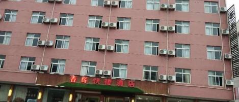 Ein mehrstöckiges Hotel mit roter Fassade und Klimaanlagen an jedem Fenster.