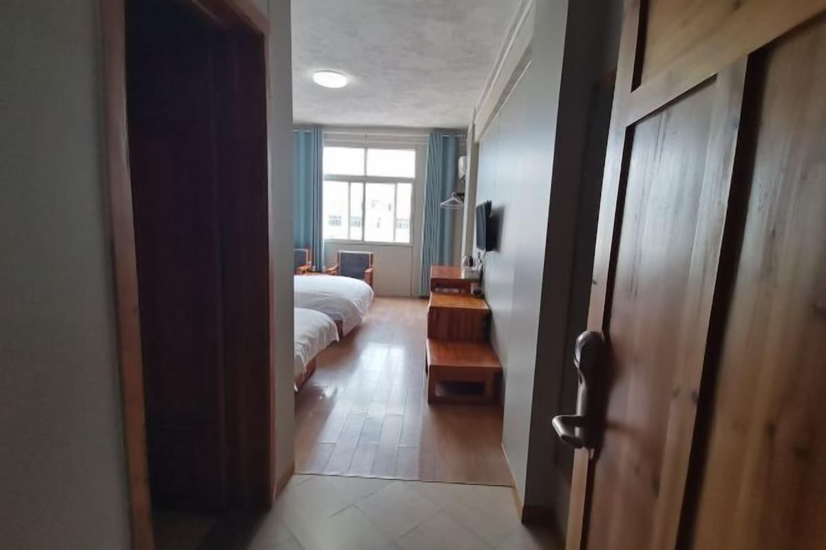 A hotel room with a bed, a desk, a chair, a TV, and a window.