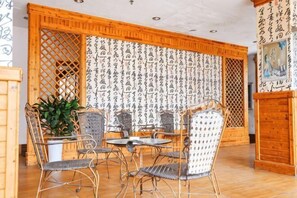Una habitación con decoración tradicional japonesa, que incluye suelo de tatami, una mesa de madera baja con sillas y un biombo decorativo con caligrafía.