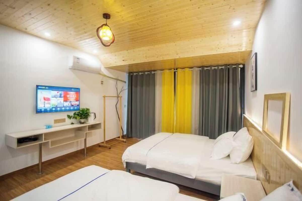 A modern hotel room with two beds, a TV on the wall, and a wooden ceiling.