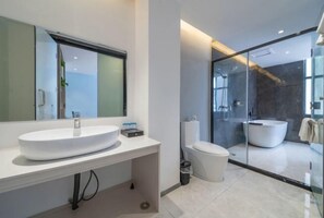 A modern bathroom with a large white sink, a toilet, and a glass-enclosed shower area.