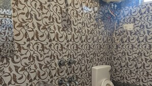 Une salle de bain avec des carreaux décorés, un lavabo, des toilettes et un seau.