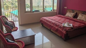 Une chambre à coucher avec un lit, une petite table, deux chaises et un balcon offrant une vue sur les montagnes.