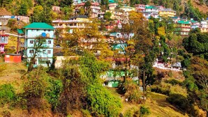 Un village perché sur une colline, avec des maisons aux couleurs vives et un arc-en-ciel bien visible.