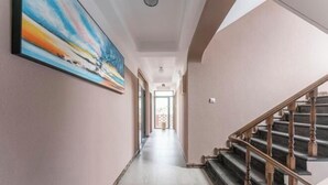 A hallway with a staircase on the right, a painting on the left, and a door at the end. - BCDJ The inn (Shengsi)