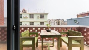 A balcony with a wooden table and chairs, a potted plant, and a view of buildings in the background. - BCDJ The inn (Shengsi)