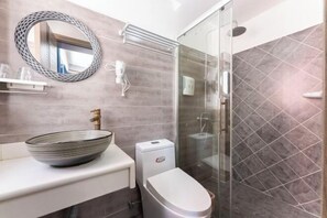 A modern bathroom with a round mirror, a vessel sink, a toilet, and a glass shower enclosure. - BCDJ The inn (Shengsi)