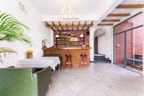 Uma área de bar com banquetas, balcão e luminária pendente.