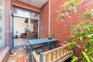 A patio with a table and bench, a brick wall, and a door leading to an interior space. - BCDJ The inn (Shengsi)