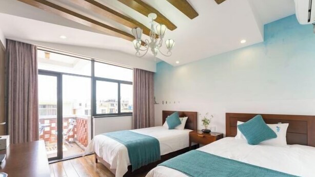 A hotel room with two beds, a large window, a chandelier, and a balcony view. - BCDJ The inn (Shengsi)