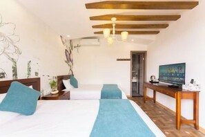 A hotel room with two beds, a wooden desk, a television, and a wall with a floral mural. - BCDJ The inn (Shengsi)
