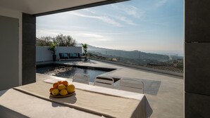 A modern outdoor seating area with a table set for a meal, overlooking a scenic landscape. - Amazing 4 bedroom Villa with sea view pool (Alella Parc)