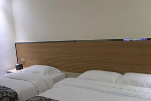 Quarto de hotel com duas camas, uma cabeceira de madeira e uma mesa de cabeceira com abajur.